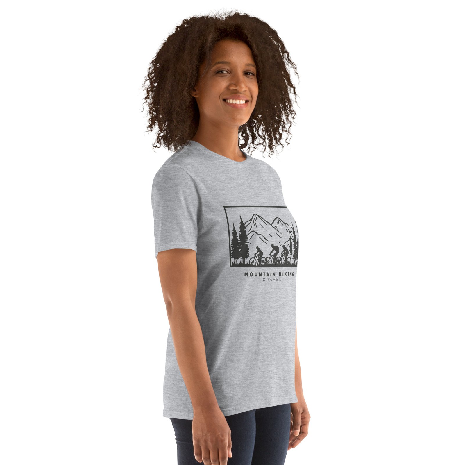 Camiseta gris claro para mujer con diseño de ciclistas en ruta rodeados de montañas y árboles sobre fondo blanco.